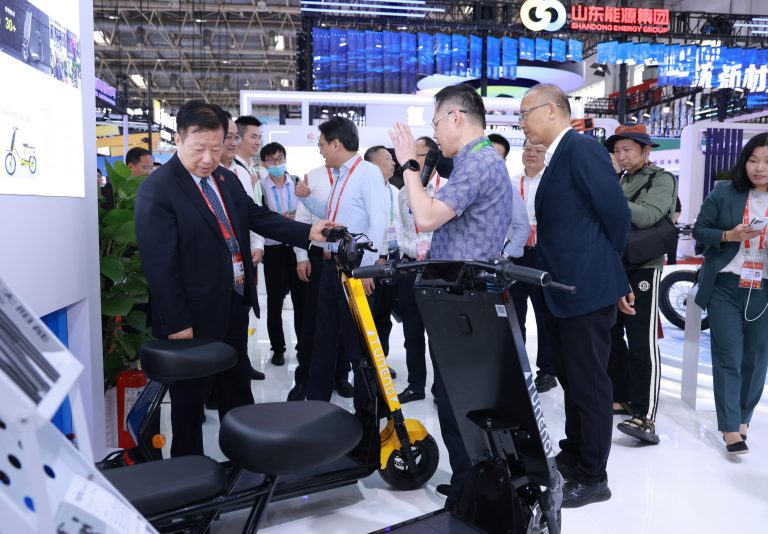 Laineng CEO Ding Boming presenting yellow Tuneng solar electric scooter to Jiangsu Vice Governor Fang Wei during official visit at China International Supply Chain Promotion Expo CISCE Beijing