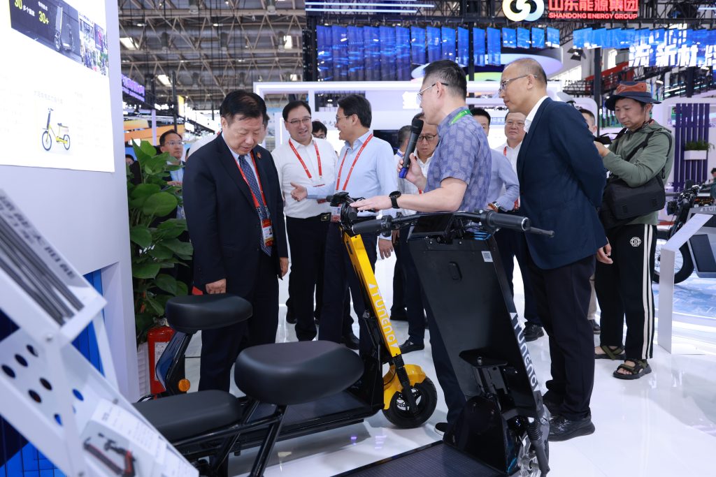 Laineng CEO Ding Boming presenting yellow Tuneng solar electric scooter to Jiangsu Vice Governor Fang Wei during official visit at China International Supply Chain Promotion Expo CISCE Beijing
