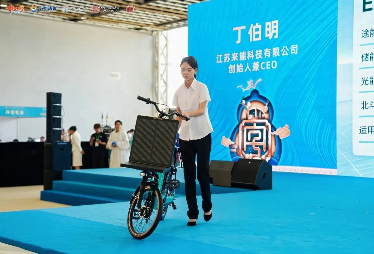 Laineng E03 solar bike on stage with founder and CEO Ding Boming backdrop